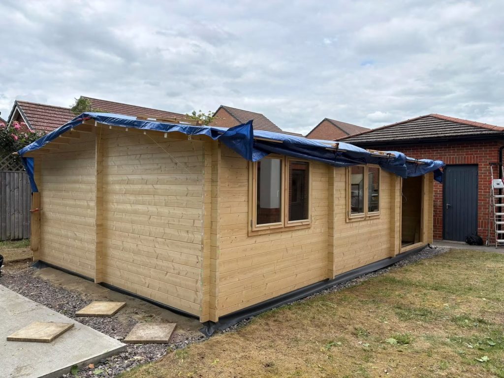 A workshop shed with blue tarpaulin on the roof.